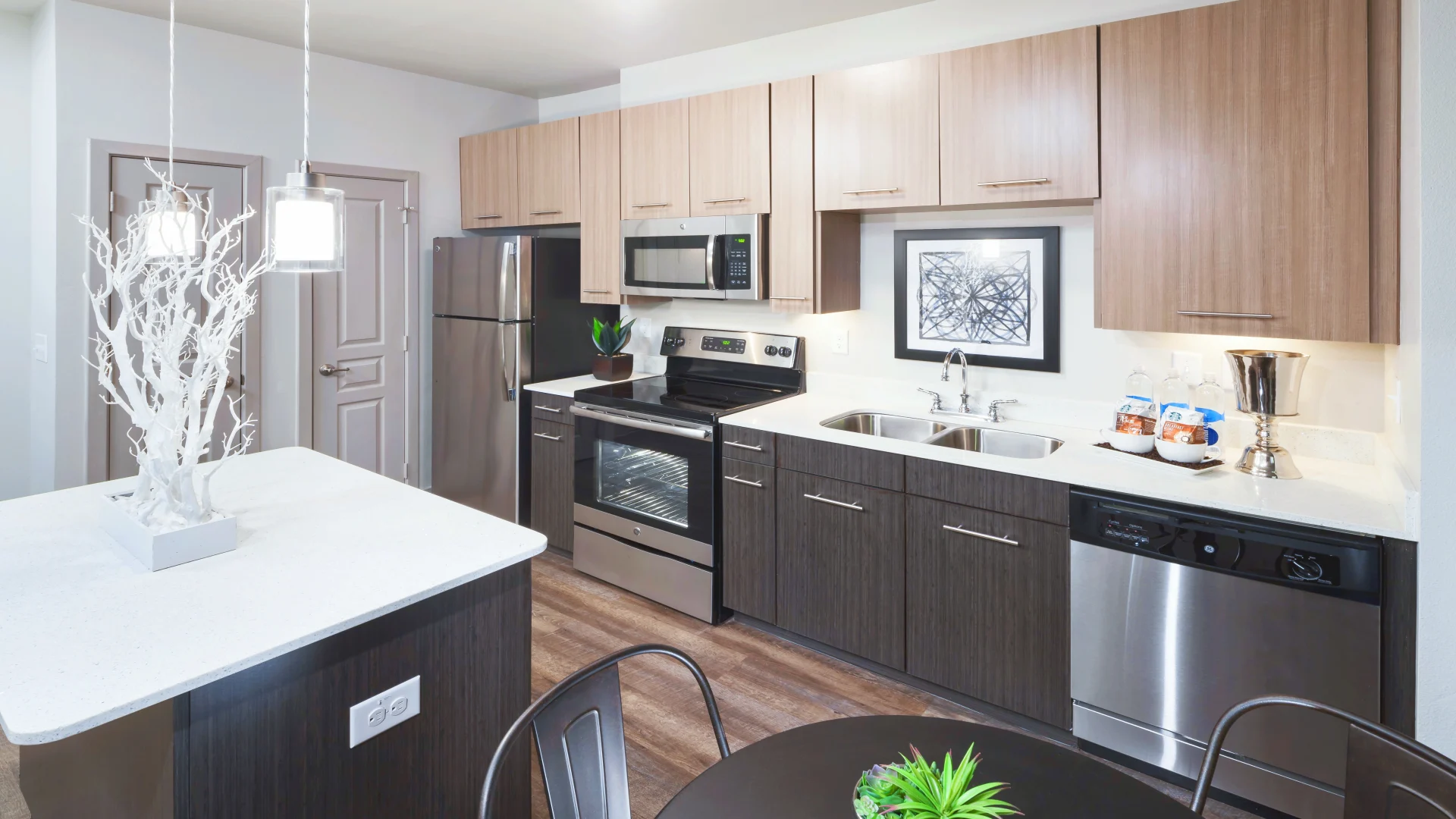 a kitchen with stainless steel appliances and wood floors at The Anatole at  Pines