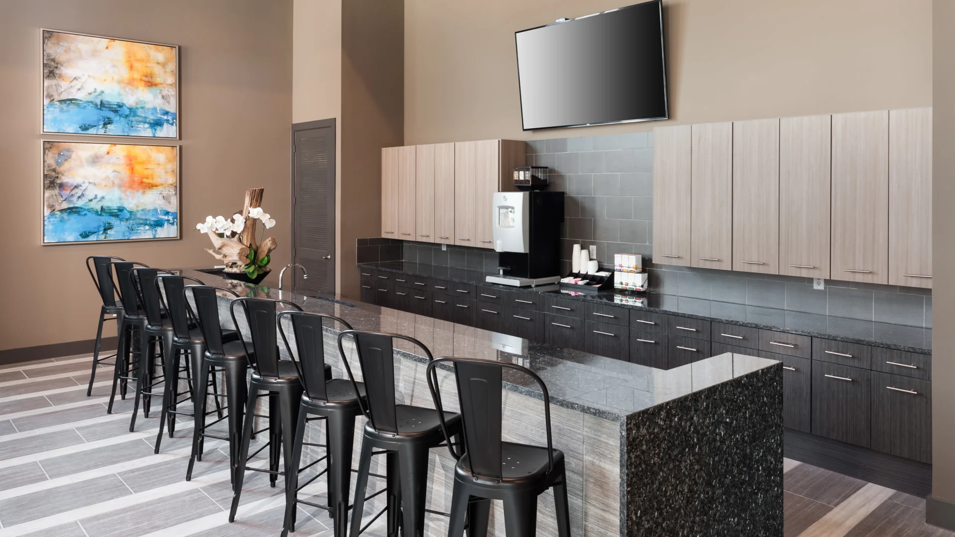 a modern kitchen with bar stools and a television at The Anatole at  Pines